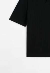 Top nero a maniche corte con scollo a V realizzato in tessuto a costine testurizzato, caratterizzato da una vestibilità comoda e bordi puliti.