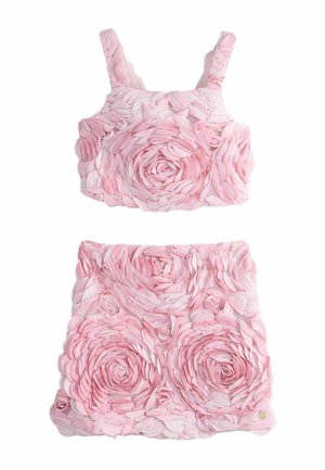 Ensemble deux pièces rose avec des motifs floraux en relief 3D formant des rosettes sur le crop top et la mini jupe.