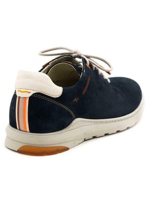 Zapatilla de ante azul marino con talón blanco, suela gris claro y rayas de acento naranjas. Presenta una superficie texturizada y un diseño con cordones.
