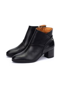 Bottes de cheville en cuir noir avec un bout pointu, un panneau arrière texturé et un talon carré de hauteur intermédiaire. L'intérieur présente une doublure beige.
