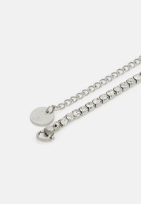 Bracelet en argent avec un design à maillons de chaîne, orné d'une rangée de strass transparents et d'une fermeture à fermoir mousqueton. Comprend une étiquette circulaire.