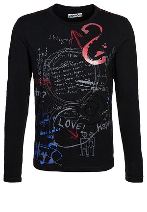 Hombre vestido con camiseta de manga larga negra con estampado, vaqueros grises, zapatillas negras y blancas, con un bolso de cuero marrón colgado del hombro.