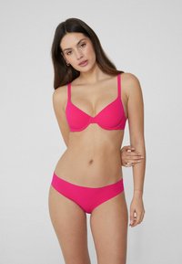 Sujetador fucsia y parte inferior de bikini a juego, hechos de una tela suave, con tirantes finos y un diseño simple y sin costuras.