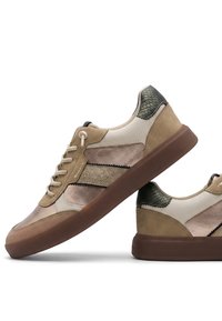Ζευγάρι μπεζ και καφέ sneakers με κορδόνια, διακοσμημένα με υφές και χοντρές καφέ σόλες σε λευκό φόντο.