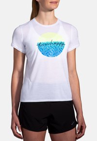 Camiseta deportiva blanca de manga corta con un gráfico circular en azul y amarillo claro, que presenta texto repetido en una fuente moderna.