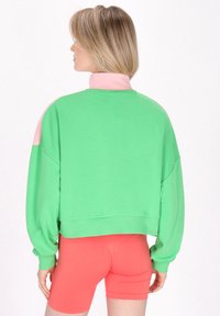Sudadera color bloqueada en verde y rosa con un alto cuello, un corte holgado y puños acanalados. Textura suave para mayor comodidad.