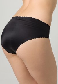 Mutande nere seamless con un elastico ondulato in vita, texture liscia e design minimalista, che enfatizza il comfort e la vestibilità.
