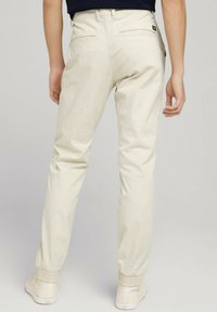 Beżowe bawełniane spodnie o zwężanym kroju, z elastycznymi ściągaczami, dwoma tylnymi kieszeniami i małym logo marki z tyłu.