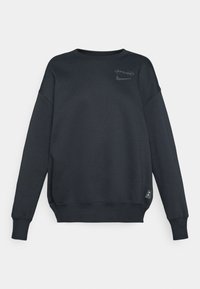 Felpa nera a girocollo con loghi degli Spurs e di Nike sul petto e un piccolo emblema del Tottenham Hotspur vicino all'orlo.