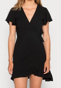 Robe noire à manches courtes et volantés, décolleté en V, lien sur le côté et ourlet froncé. Tissu doux et texture lisse.