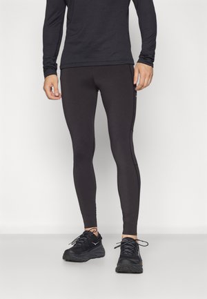 Black athletic leggings made of stretchy material with a fitted design and side accents. Paired with black running shoes.