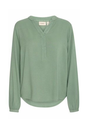 Hellgrüne Bluse mit langen Ärmeln und strukturiertem Finish, V-Ausschnitt und elastischen Ärmelbündchen. Abgerundeter Saum mit dezentem Stickdetail.