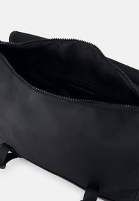 Interno di una borsa in nylon nera con chiusura a zip. Presenta una piccola tasca con zip e una texture liscia, progettata per organizzazione e accessibilità.