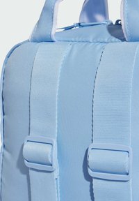 Mochila de tela azul con superficie texturizada, correas ajustables y herrajes de plástico. Presenta un asa en la parte superior y costuras reforzadas.