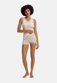 Set di top senza maniche bianco e pantaloni corti realizzati in tessuto morbido, con dettagli in pizzo sulle spalline e sull'orlo, dal design aderente e dalla texture liscia.