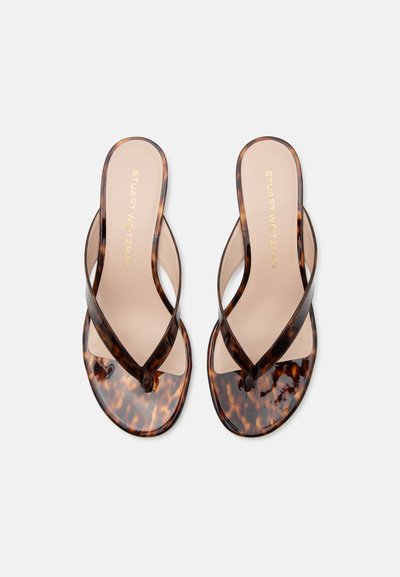 Paire de tongs à motif écaille de tortue avec semelles beiges et marque « Stuart Weitzman », vues de dessus sur fond blanc.