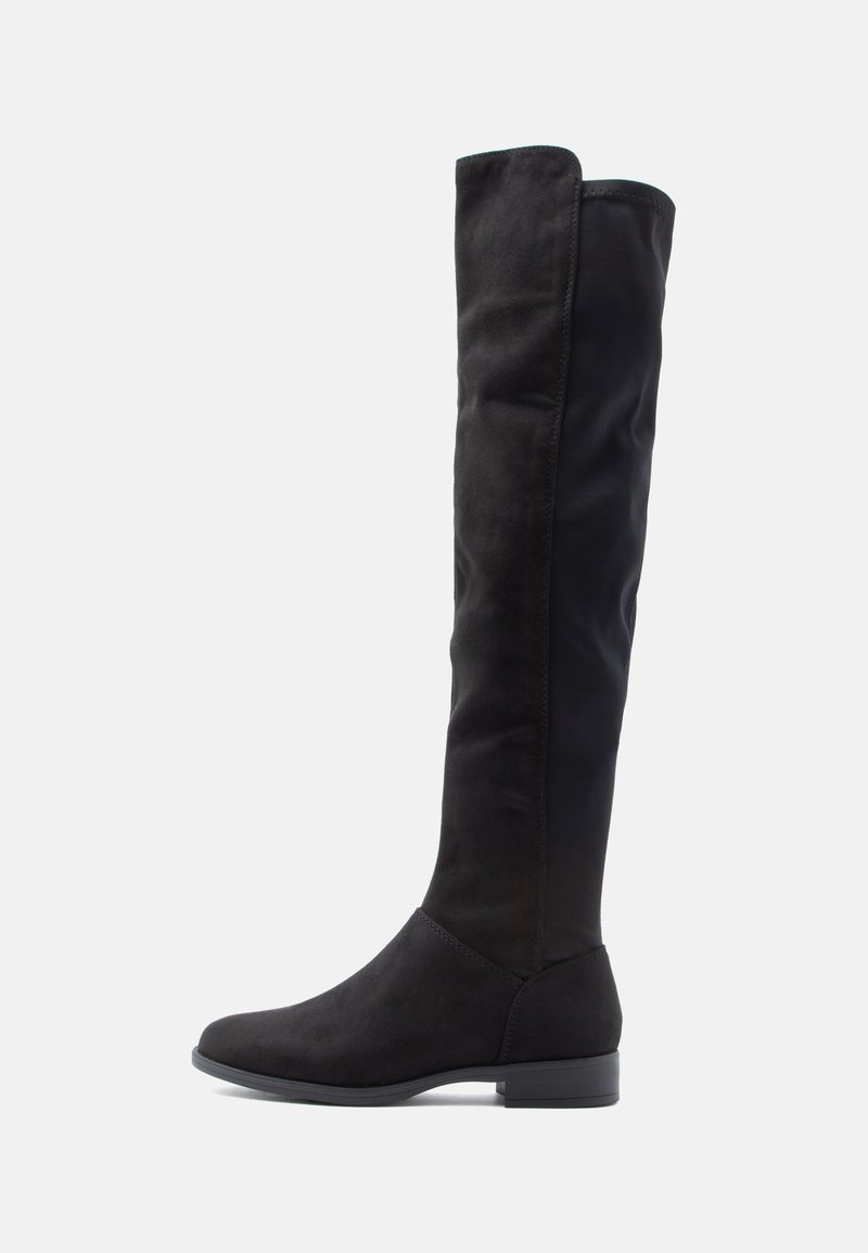 Botte noire plate montant jusqu'au genou avec bout arrondi et talon bas, présentant un mélange de textures lisses et semblables au daim.