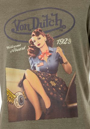 T-shirt vert avec une illustration de style vintage d'une femme en blouse bleue et jupe à motifs, accompagnée du texte "Von Dutch" et "Welcome Aboard 1929."