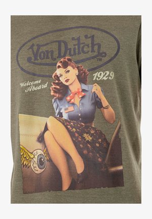 T-shirt vert avec une illustration de style vintage d'une femme en blouse bleue et jupe à motifs, accompagnée du texte "Von Dutch" et "Welcome Aboard 1929."