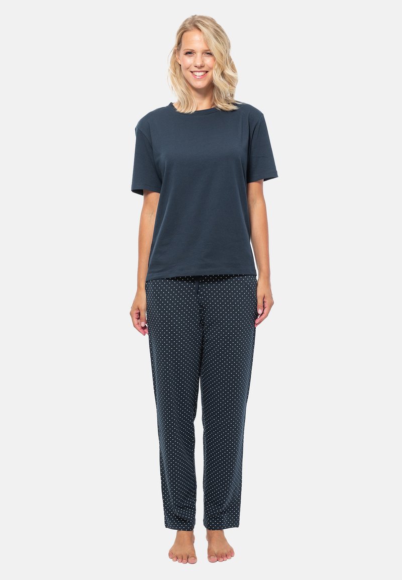 T-shirt en coton bleu marine à manches courtes associé à un pantalon sombre à pois blancs. Coupe décontractée, tissu doux, sans fermetures visibles.