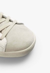 Sneaker con tomaia in morbido suede grigio chiaro e dettagli in pelle bianca liscia. Forma della punta arrotondata e suola in gomma testurizzata. Inclusi lacci piatti.