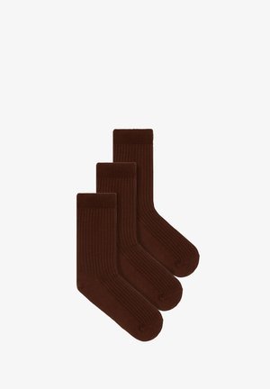 Brązowe, prążkowane skarpetki o snugowym dopasowaniu, zestawione z casualowymi niebieskimi dżinsami, ukazującymi fakturowany materiał i długość do kostki.