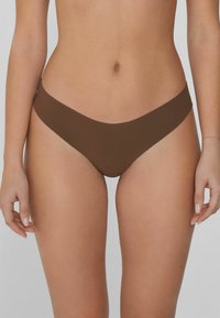 Brązowy bikini w formie dolnej z niskim stanem, gładką teksturą i minimalnym zakryciem, wykonany z elastycznego, lekkiego materiału.