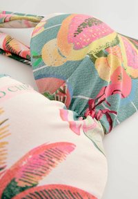 Ziedu raksta audums izceļas ar dzīvām krāsām, piemēram, rozā, dzeltenā un zaļā krāsā. Materiāls ir mīksts ar savāktu dizainu centrā.