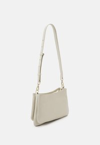 Bolso de hombro de cuero gris claro con una correa larga ajustable y una parte superior con cremallera. Presenta herrajes en tono dorado y una textura suave.