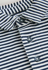 Marineblå og hvidstribet polo t-shirt med krave, med fire mørke knapper ved knapstolpen, lavet af et blødt strikket materiale.