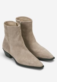 Beżowe zamszowe botki za kostkę z ostrym czubkiem, bocznym zamkiem błyskawicznym i niskim, kwadratowym obcasem. Gładkie wnętrze i teksturowana powierzchnia na zewnątrz.