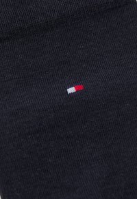 Marineblaue Socken aus weichem Stoff, mit einem kleinen rot-weißen-blauen Logo, das an der Seite gestickt ist. Glatte Textur und Standardlänge.