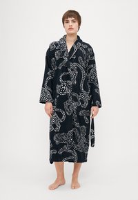 Mörkblå badrock med ett vitt djurmönster, tillverkad av texturerad tyg, med långa ärmar, en omlottdesign och ett matchande knytbälte.