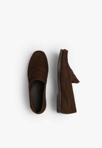 Mocasines de ante marrón con un acabado suave, que presentan un perfil bajo, costuras en contraste y una suela de goma texturizada y flexible.