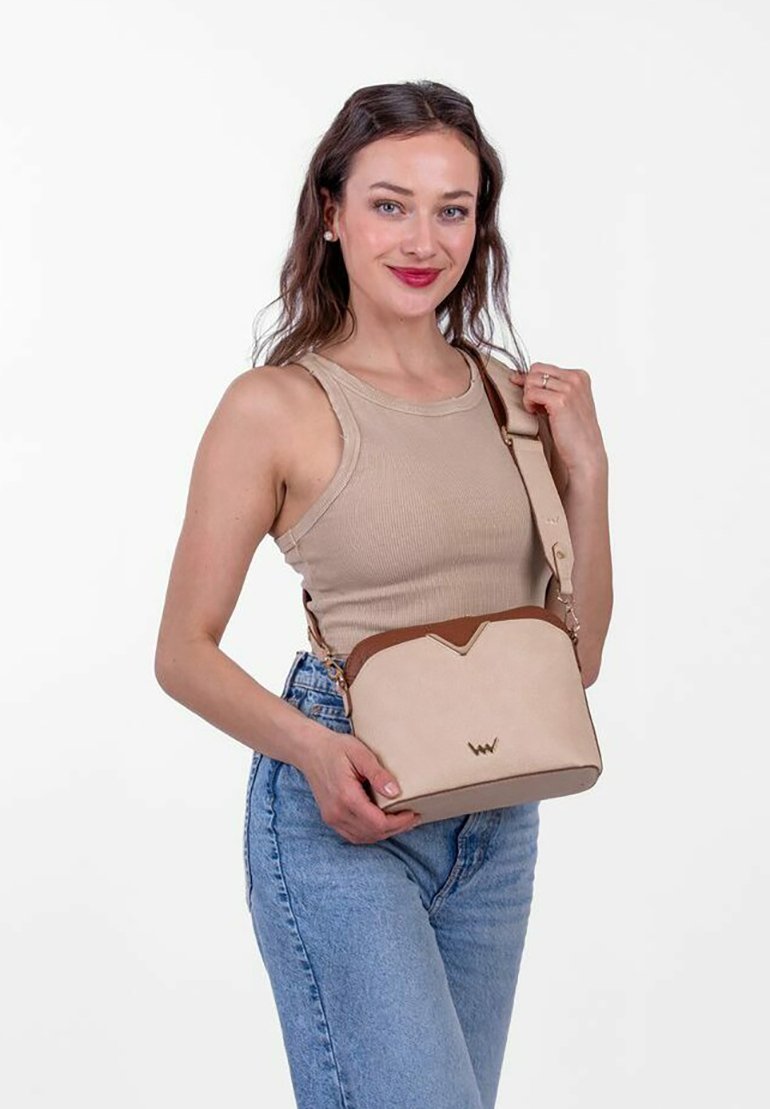 Beige Umhängetasche mit einem braunen Akzent oben. Verfügt über ein elegantes Design, eine glatte Textur und ein gesticktes Logo auf der Vorderseite.