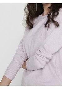 Pull violet en tissu doux, doté de manches longues et de poignets côtelés. Le design est une coupe décontractée avec un col rond.