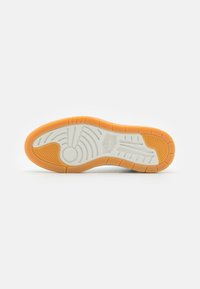 Semelle de chaussure avec une bordure orange et un centre blanc, présentant des motifs de semelle texturés et des logos Nike et Jordan embossés.