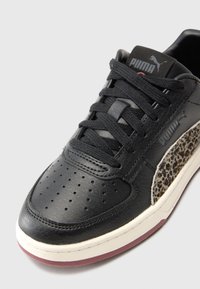 Sneaker in pelle nera con punta perforata, lacci piatti e pannello laterale con stampa leopardata. Presenta una parte superiore morbida e testurizzata e suola bianca.