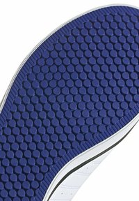 Suela de zapatilla blanca con una base de goma azul que presenta un patrón de puntos para tracción, bordeada por una delgada línea negra y con un lado texturizado.