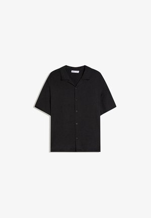 Chemise noire à manches courtes avec col camp et boutons, présentée à plat sur un fond blanc.