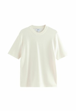 Kratki rukavi krem T-shirt napravljen od teksturirane tkanine s okruglim izrezom i opuštenim krojem. bez uzoraka ili dodatnih ukrasa.
