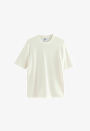T-shirt crème à manches courtes en tissu texturé, avec un col rond et une coupe décontractée. Sans motifs ni embellissements supplémentaires.