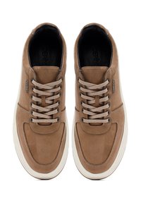 Zapatillas de cuero marrón con una textura suave, que presentan cordones beige, detalles de costura y una suela de goma blanca.