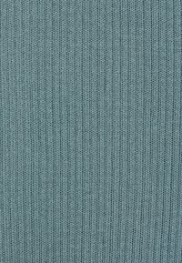 Tissu côtelé texturé dans une couleur teal atténuée, montrant de fines lignes verticales et une apparence douce et tricotée. Aucun motif ou accent visible.