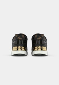 Baskets noires et marron à motif avec semelles blanches et accents dorés brillants sur le talon embossés du mot « GUESS », vues de dos.