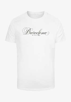 Fehér pamut póló, amelyen középen a "Barcelona" felirat látható kurzivával, alatta kisebb betűméretben pedig a "SPAIN" felirat.