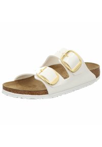 White slide sandal with two adjustable gold buckles, cork footbed, and white rubber sole. Smooth upper material with a minimalist design.