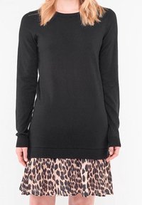 Svart långärmad topp med ribbat mönster, i kombination med en genomskinlig klänning med leopardmönster. Kjolen har en plisserad design i fållen.