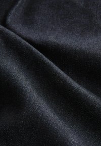 Teléfono negro con una textura suave, un brillo sutil y un tejido fino. El material parece suave y ligeramente reflectante con tonos variados.