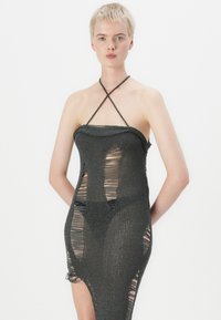 Black knitted dress with a halter neck, featuring cut-out sections and a sheer texture, accentuating a fitted silhouette.